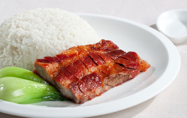 一碗"标准"的叉烧饭,叉烧铺在白饭上面,旁边围几条油菜.